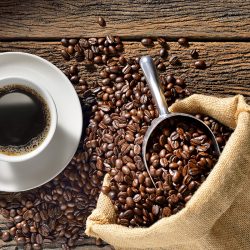 Cup of coffee and coffee beans on wooden table